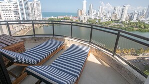 Een balkon met twee loungestoelen en uitzicht op een stadshemelbeeld en water.