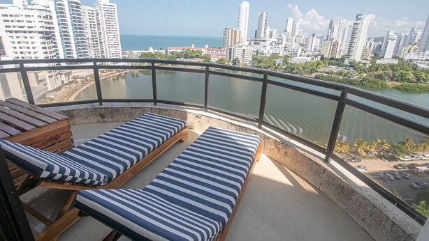 A balcony with two lounge chairs and a view of a city skyline and water.