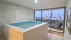 A modern bathroom with a large bathtub, a glass shower enclosure, and a city view through large windows.