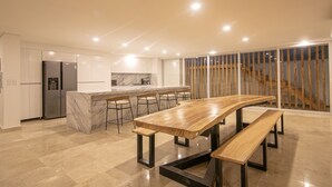 A modern kitchen with a marble island, stainless steel appliances, and a wooden dining table with benches. - 16 Bedroom in Clock Tower Plaza with Private Pool (Cartagena)