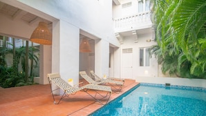 Zona de piscina con sillones de descanso y una piscina con azulejos.