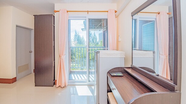 A room with a piano, a sliding glass door to a balcony, and a large mirror. - Supatranai Home Cha-am (Cha-am)