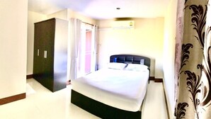 A bedroom with a bed, a wardrobe, and a door leading to another room. - Supatranai Home Cha-am (Cha-am)