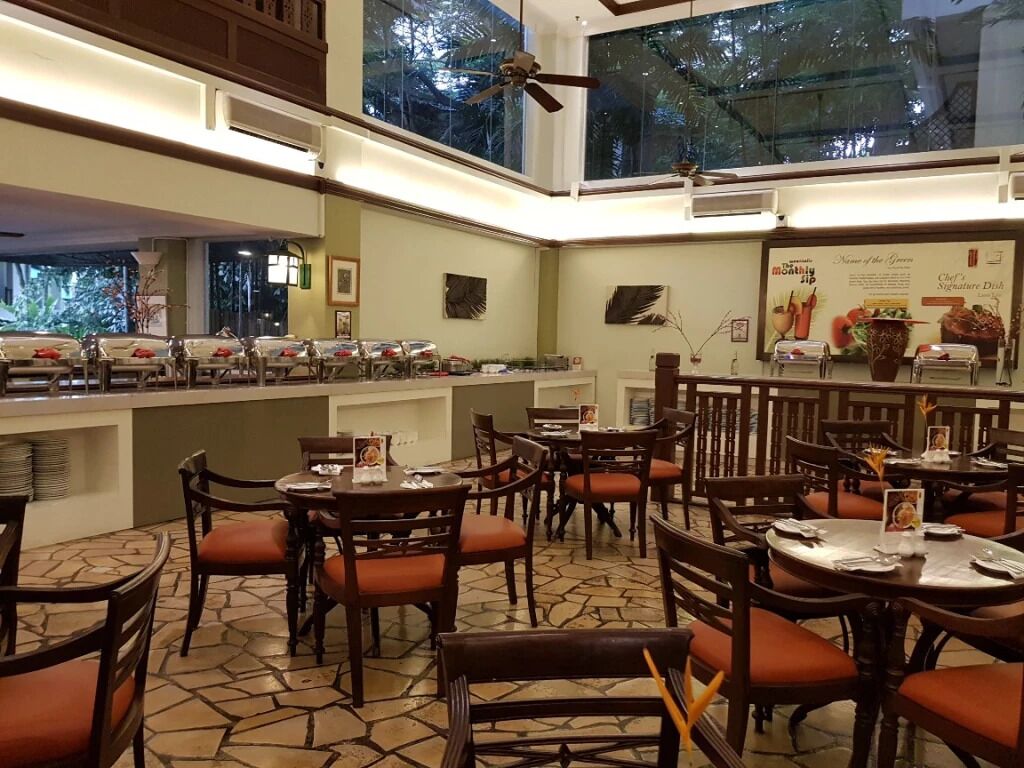 A restaurant with multiple tables and chairs, a buffet area, and a ceiling fan.