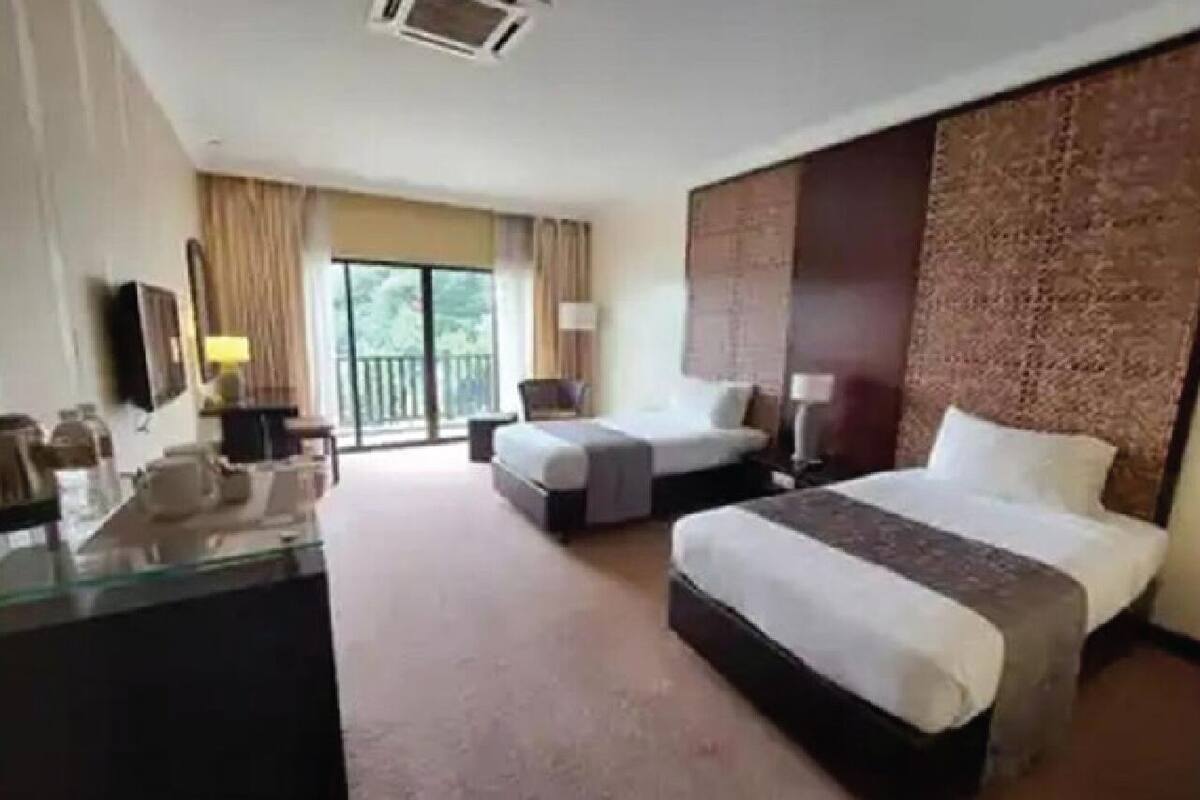 A hotel room with two beds, a desk, and a large window.