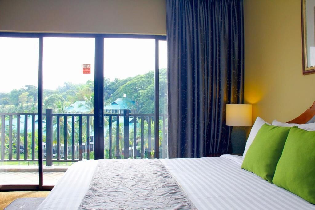 Una camera d'hotel con un letto grande, un balcone affacciato sul verde e una porta scorrevole.