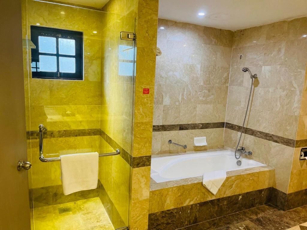 A bathroom with a glass shower enclosure, a bathtub, and a vanity with a mirror.