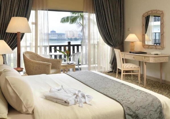 A hotel room with a bed, a desk, a chair, and a view of a body of water.