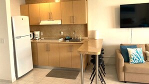Una cucina compatta con mobili in legno, forno integrato, lavello e un piccolo tavolo da pranzo.