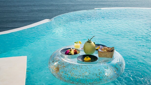 A clear view of a swimming pool with a floating dining setup featuring a variety of food items and drinks. - Private Jet Villa (Pecatu)