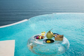 Visão nítida de uma piscina com um espaço de refeições flutuante, com diversos alimentos e bebidas.