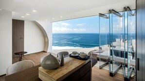 A modern room with a view of the ocean, a dining area with a table and chairs, and a seating area with cushions. - Private Jet Villa (Pecatu)