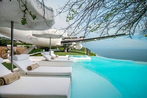 Een buitenzwembad, parasols bij het zwembad en ligstoelen