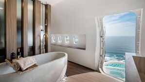 A modern bathroom with a large bathtub, a wooden vanity, and a view of the ocean through a large window. - Private Jet Villa (Pecatu)