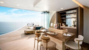 A modern, open-plan living area with a wooden deck overlooking the sea, a dining area with bar stools, and a kitchen with a built-in wine cooler. - Private Jet Villa (Pecatu)