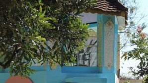 Un bâtiment aux couleurs vives, doté d’une entrée carrelée et d’un petit arbre planté dans un jardon.