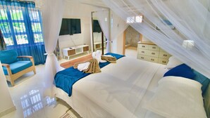 A bedroom with a bed, a chair, a vanity, and a mirror. - Sea Splash & La Petite Maison (Praslin Island)