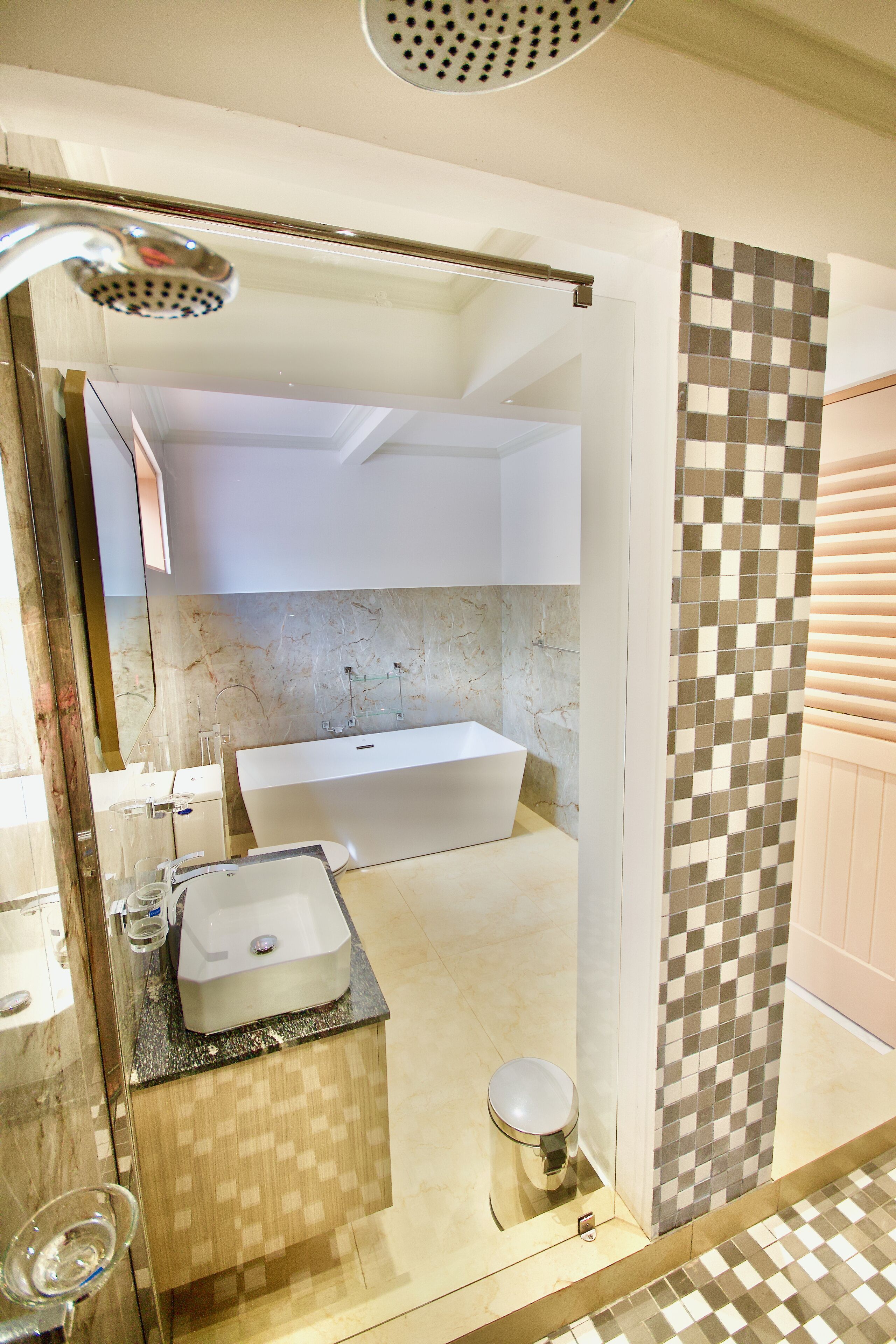 Un baño moderno con una bañera grande, cabina de ducha con mampara de vidrio y tocador con lavamanos.