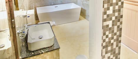 Un baño moderno con una bañera grande, cabina de ducha con mampara de vidrio y tocador con lavamanos.