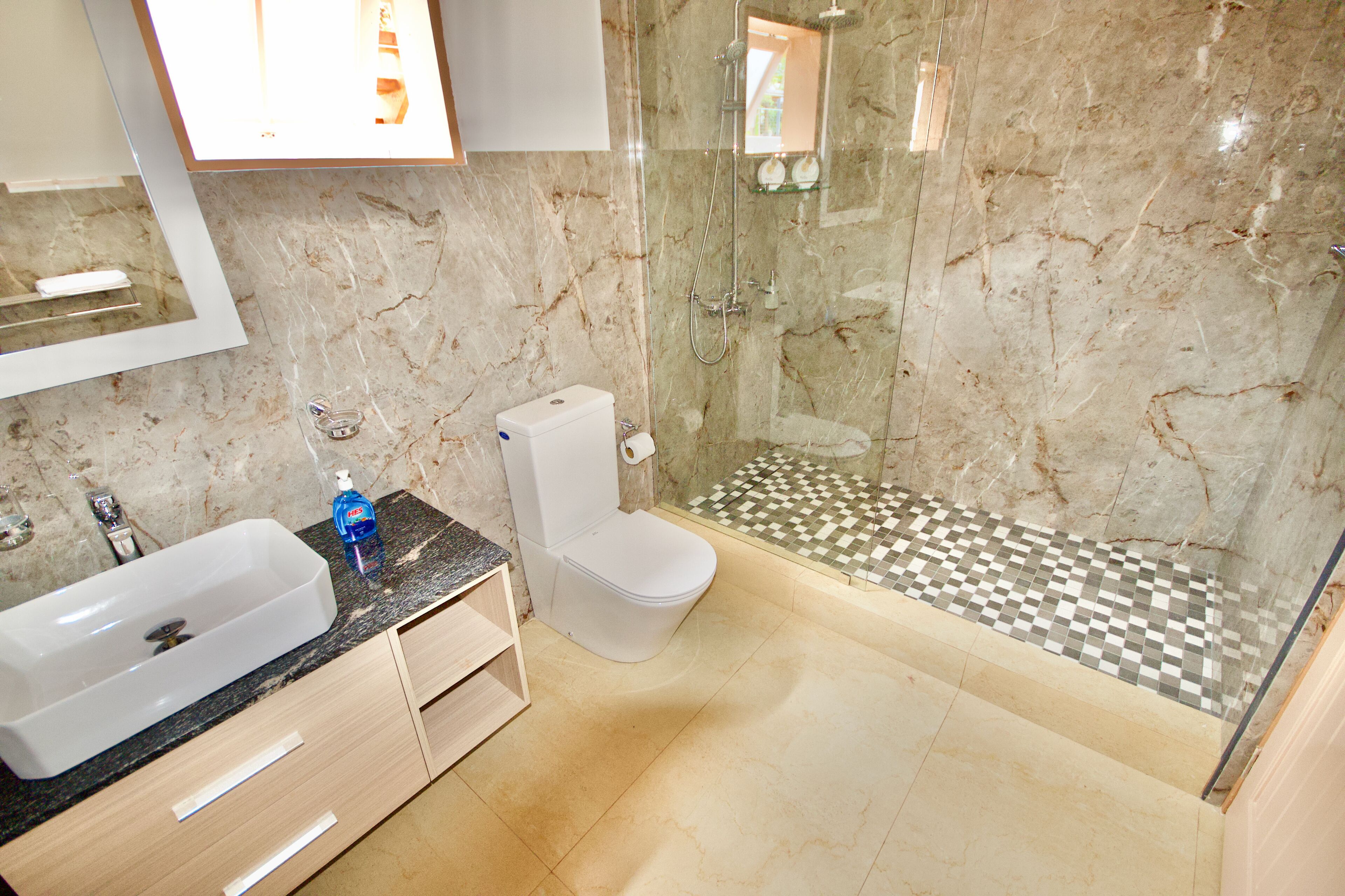 A bathroom with a marble sink, toilet, and a glass-enclosed shower area.