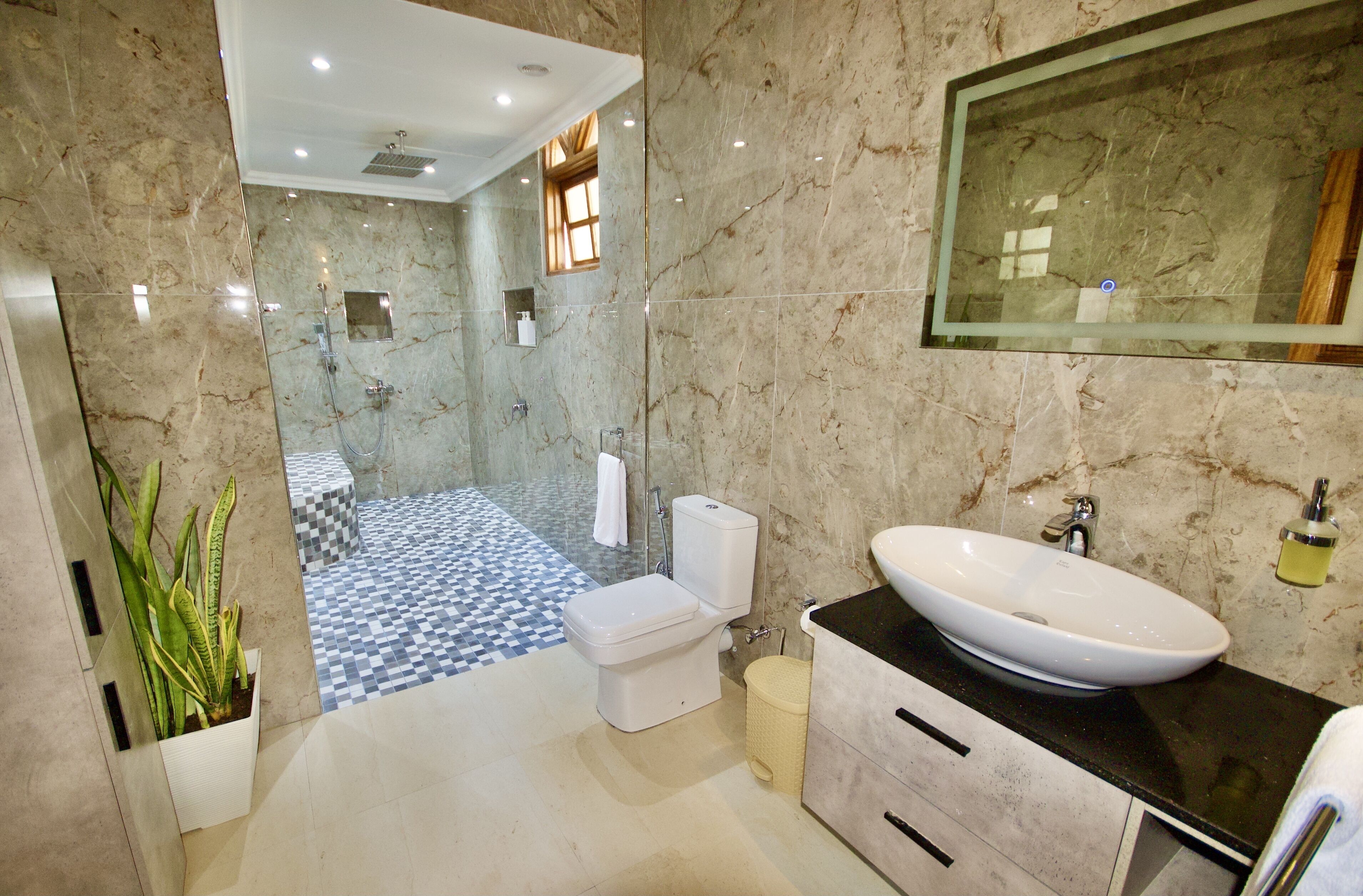 A modern bathroom with a marble floor, a white sink, and a glass-enclosed shower.