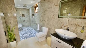 A modern bathroom with a marble floor, a white sink, and a glass-enclosed shower.
