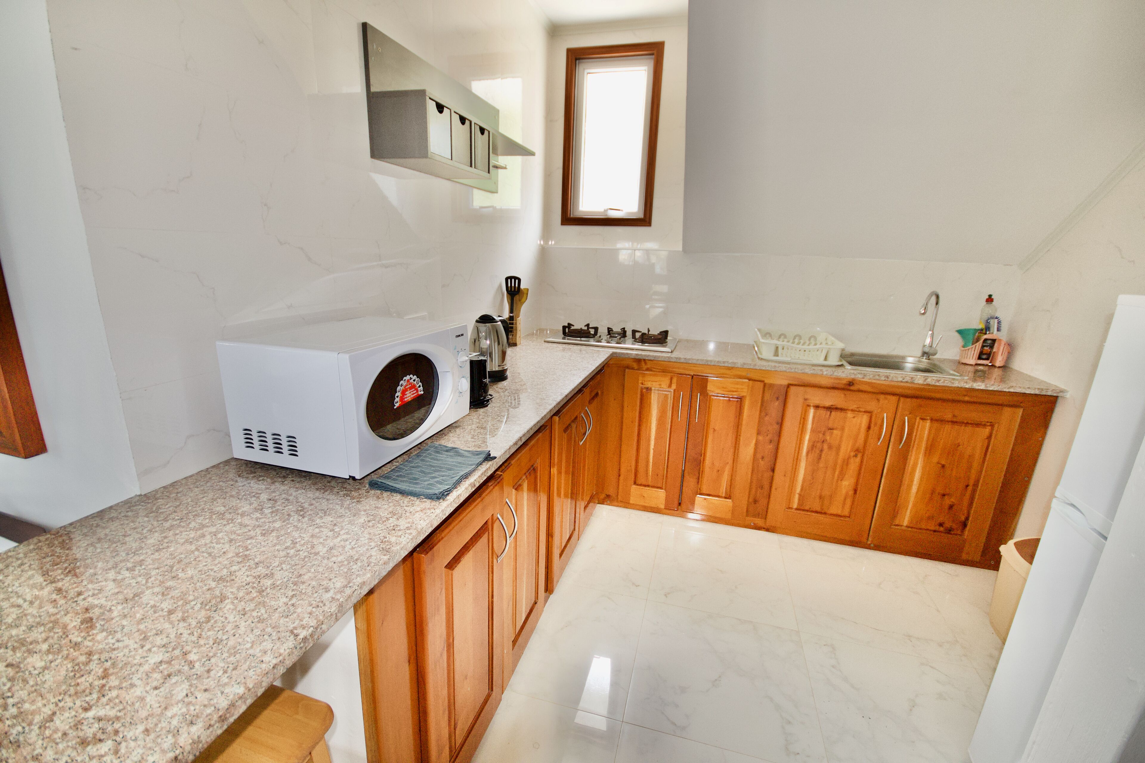 A kitchen with granite countertops, wooden cabinets, a built-in oven, and a window above the sink.
