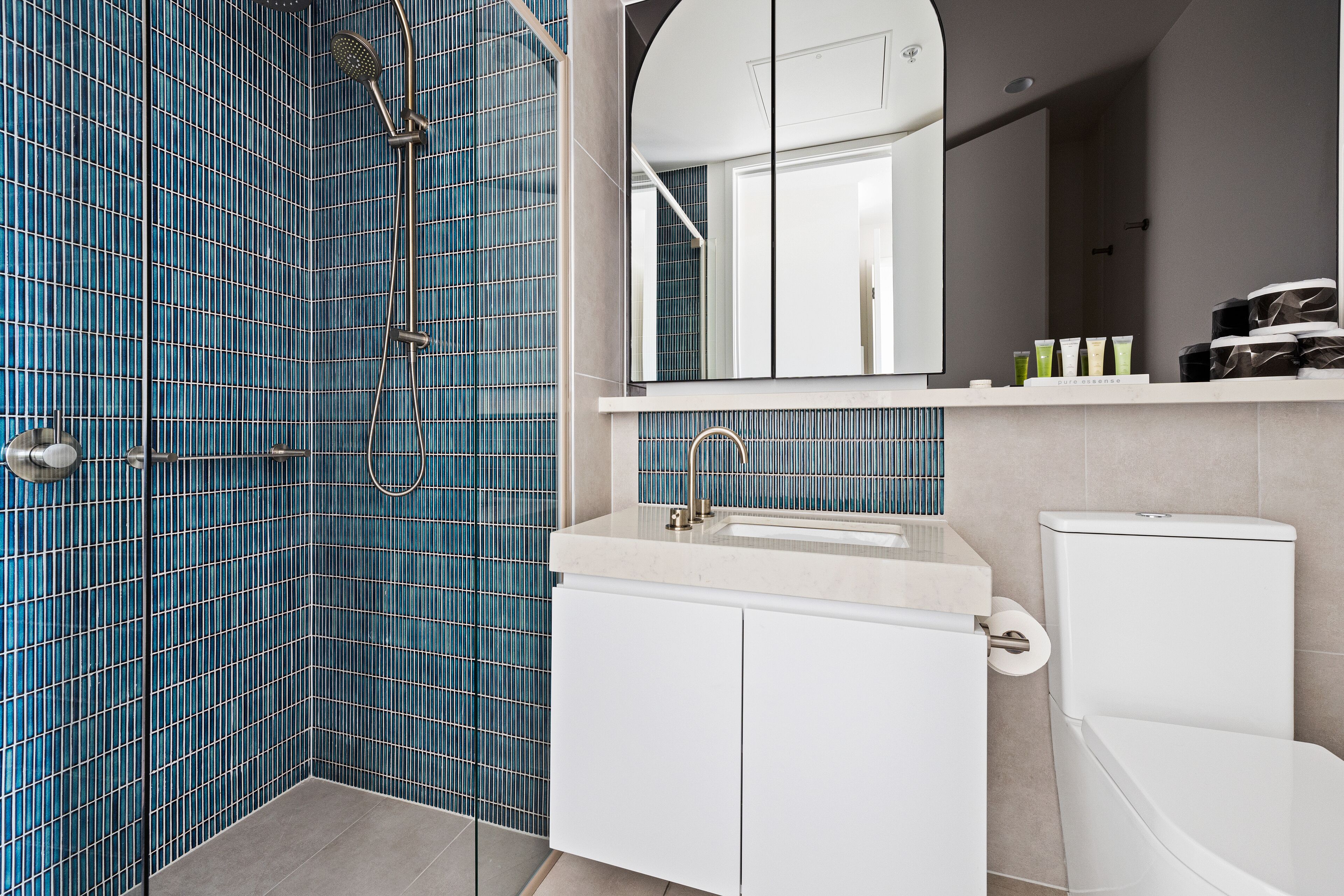 A bathroom with blue tiled walls, a white sink, and a toilet.