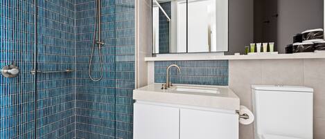 A bathroom with blue tiled walls, a white sink, and a toilet.