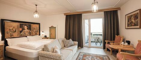 Un dormitorio con cama, sofá, sillón, mesa y balcón.