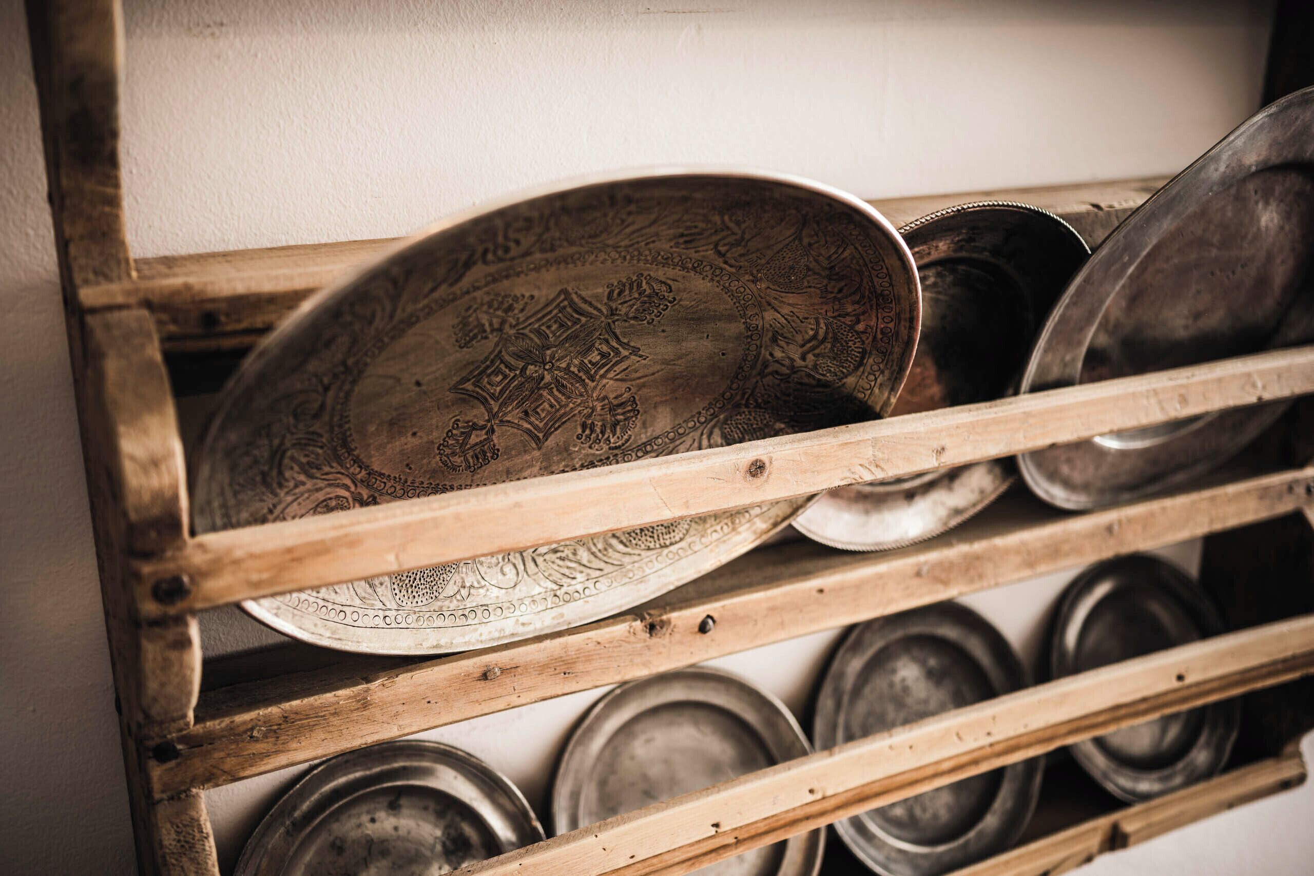 A rack of metal plates and bowls, likely used for serving food, with a wooden frame.