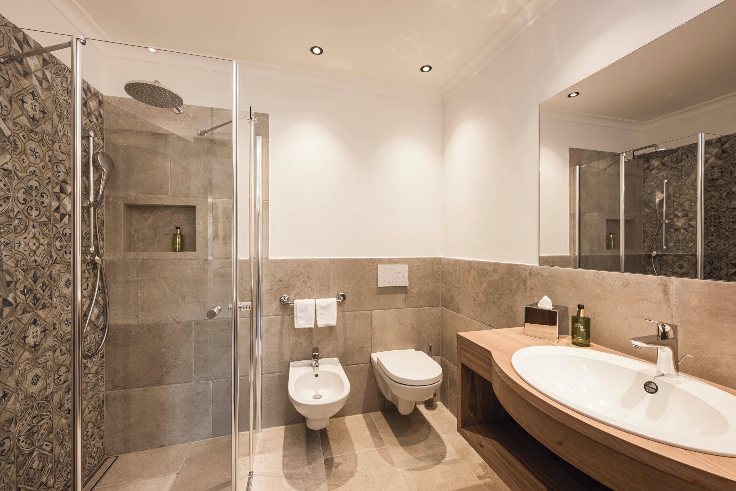 A modern bathroom with a glass-enclosed shower, a bidet, a sink, and a vanity.