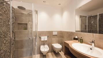 A modern bathroom with a glass-enclosed shower, a bidet, a sink, and a vanity.