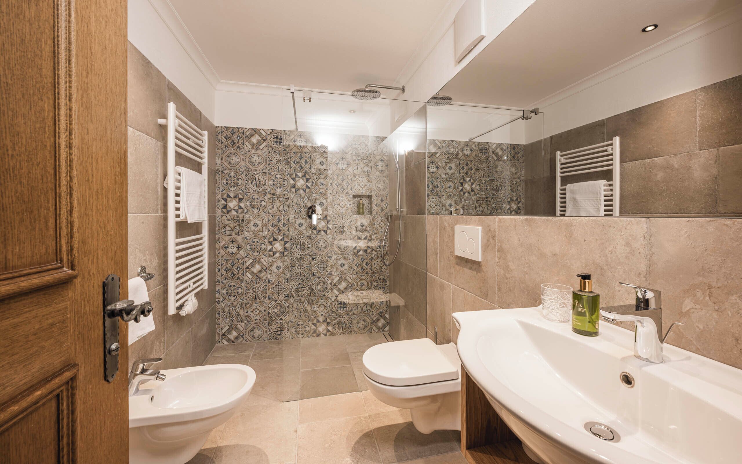 Un baño moderno con ducha, dos lavamanos y un inodoro.