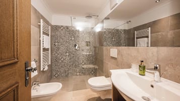 Un baño moderno con ducha, dos lavamanos y un inodoro.