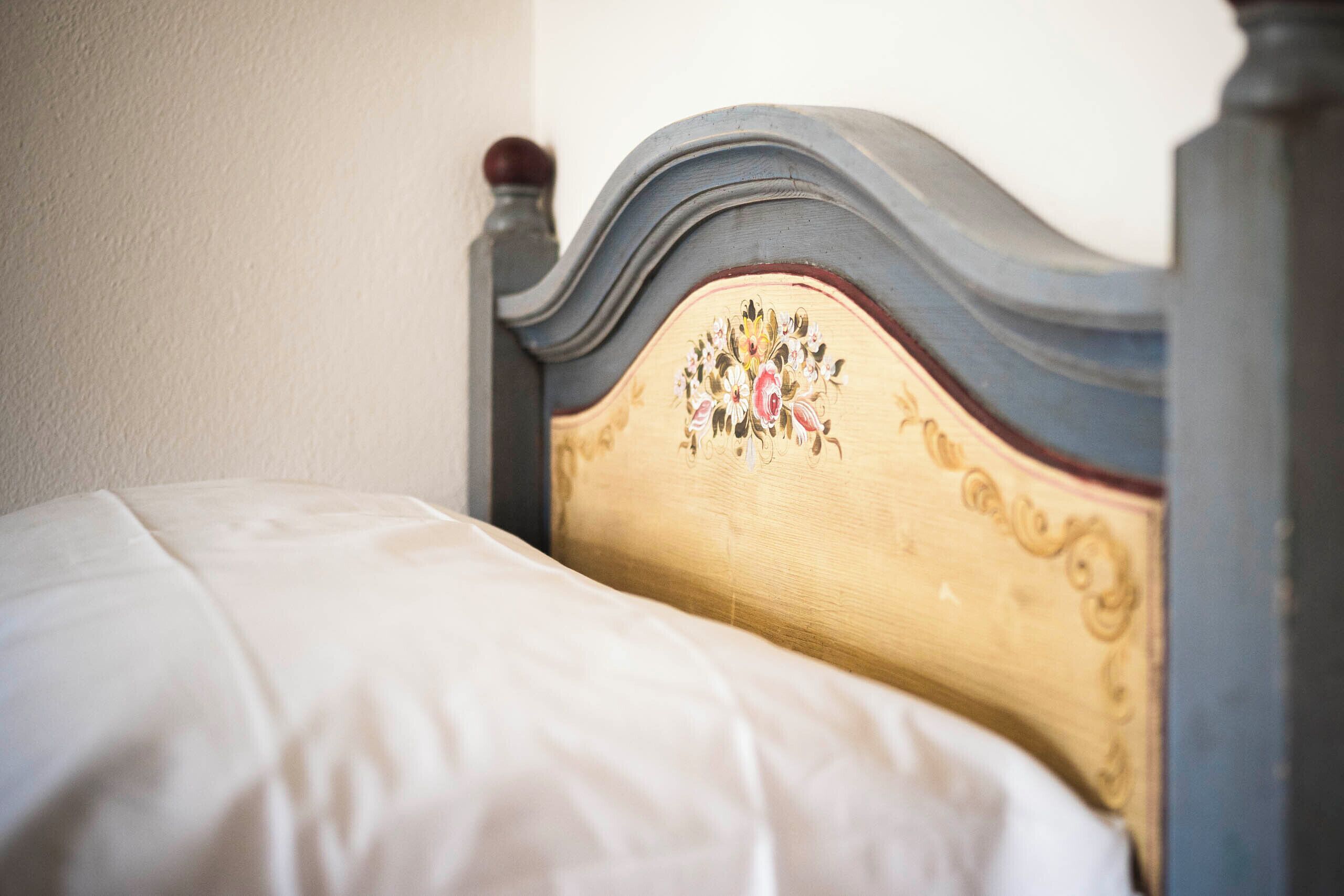 A bed with a wooden headboard featuring floral embroidery.