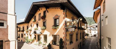 A traditional European building with a sloped roof, multiple windows, and flower boxes.