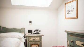 A bedroom with a bed, a dresser, a telephone, and a framed picture on the wall.