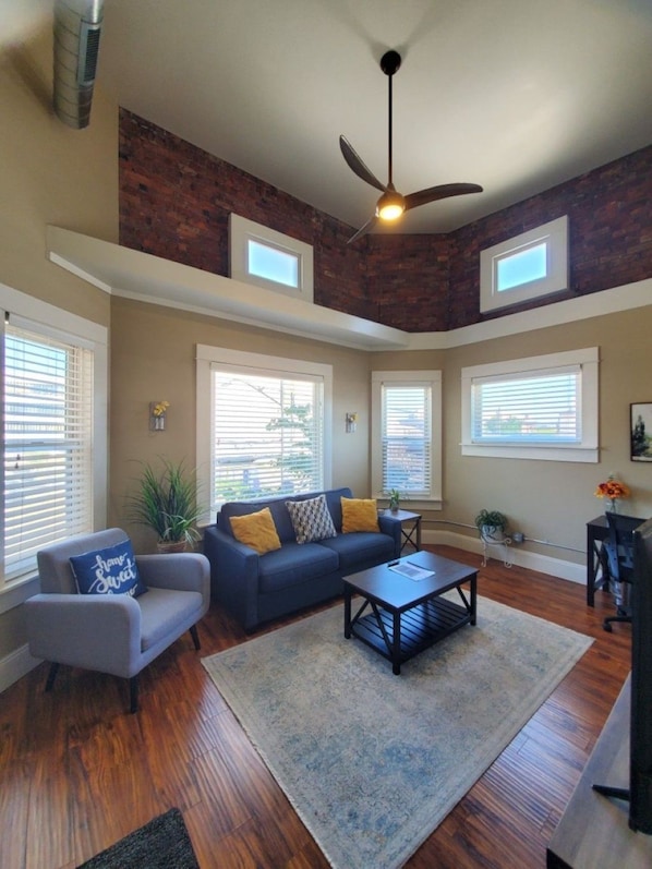 A living room with a dark blue sofa, a grey armchair, a coffee table, and a ceiling fan.