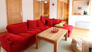 A cozy living room with a red sofa, wooden coffee table, and a mirror on the wall.