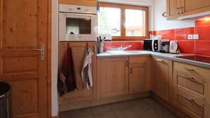 A kitchen with wooden cabinets, a microwave, a sink, and a window.