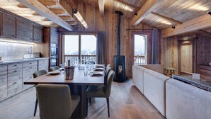 A modern kitchen with wooden beams, a dining area with a table set for four, and a large window offering a mountain view. - Spacious apartment with balcony and parking in La Rosière (Montvalezan-La Rosière)