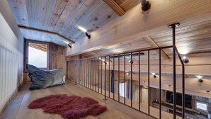 A wooden interior with a high ceiling, a metal railing, and a fur rug on the floor. - Spacious apartment with balcony and parking in La Rosière (Montvalezan-La Rosière)