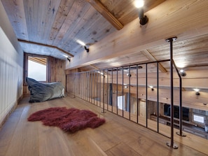 Un intérieur en bois avec un plafond haut, une rambarde en métal et un tapis en fourrure sur le sol.