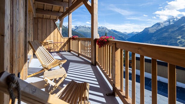 A wooden balcony with lounge chairs and a view of snow-capped mountains. - Spacious apartment with balcony and parking in La Rosière (Montvalezan-La Rosière)