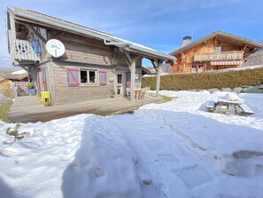 Un bâtiment en bois doté d’un balcon, d’une terrasse et dont le sol est recouvert de neige.