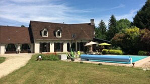 A large house with a swimming pool, a covered patio, and a well-maintained lawn. - Magnifique Villa de 14 Pers Piscine Chauffée, Jacuzzi, Sauna (Saint-Martin-des-Champs)