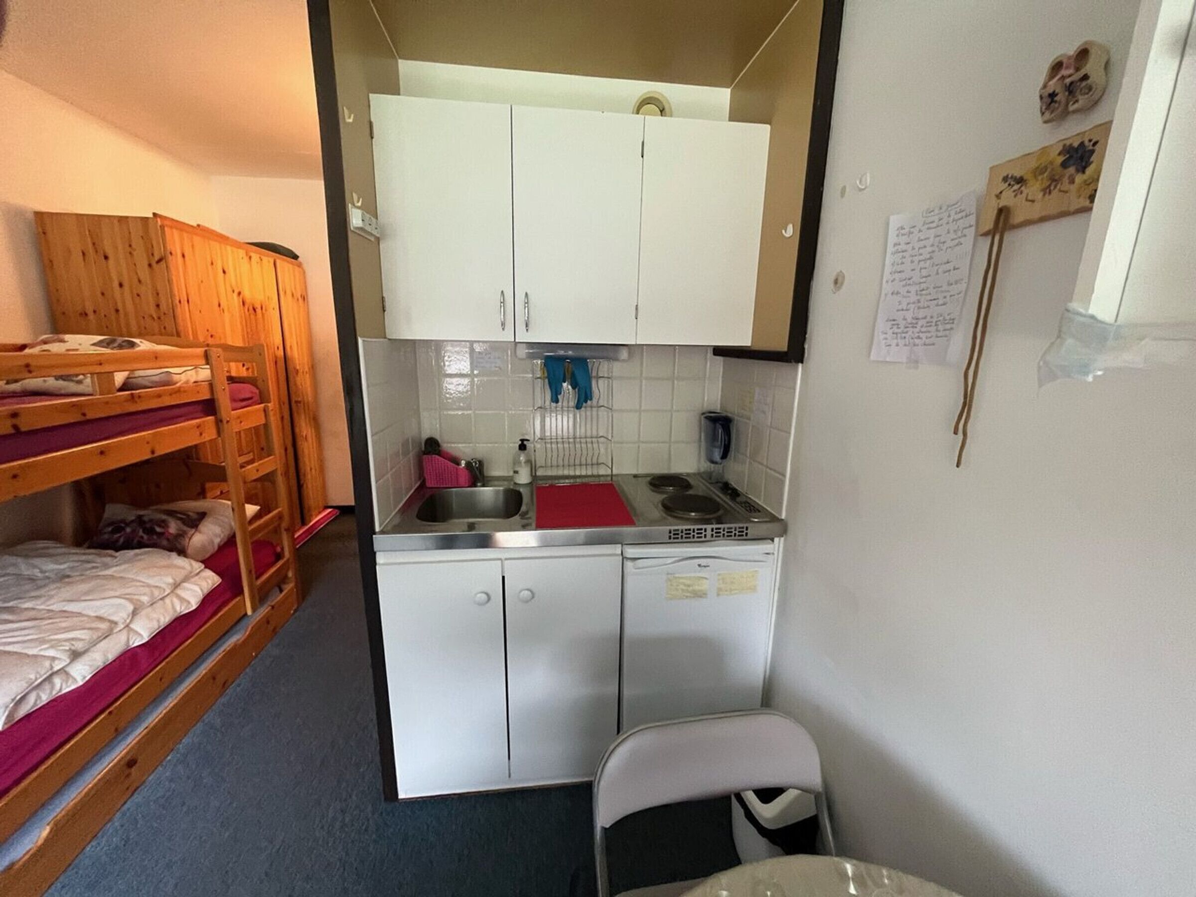 A compact room with bunk beds, a kitchenette, and a small table.