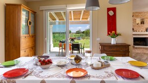 A dining area with a table set for four, a wooden cabinet, and a view of the outdoors. - 2340 Villa Il Neto by Perle di Puglia (Casarano)