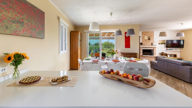 A modern kitchen with a large island, dining area, and a living room with a sofa and TV. - 2340 Villa Il Neto by Perle di Puglia (Casarano)